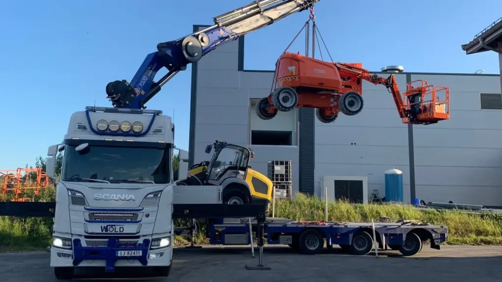 Kranbilen i Wold Kran & transport løfter en oransje lift på oppdrag. Prosjektene er ofte varierte.